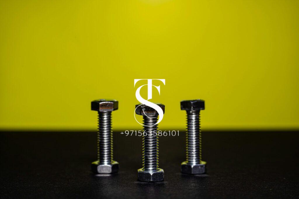 Close-up image of three steel bolts standing upright against a contrasting yellow background.