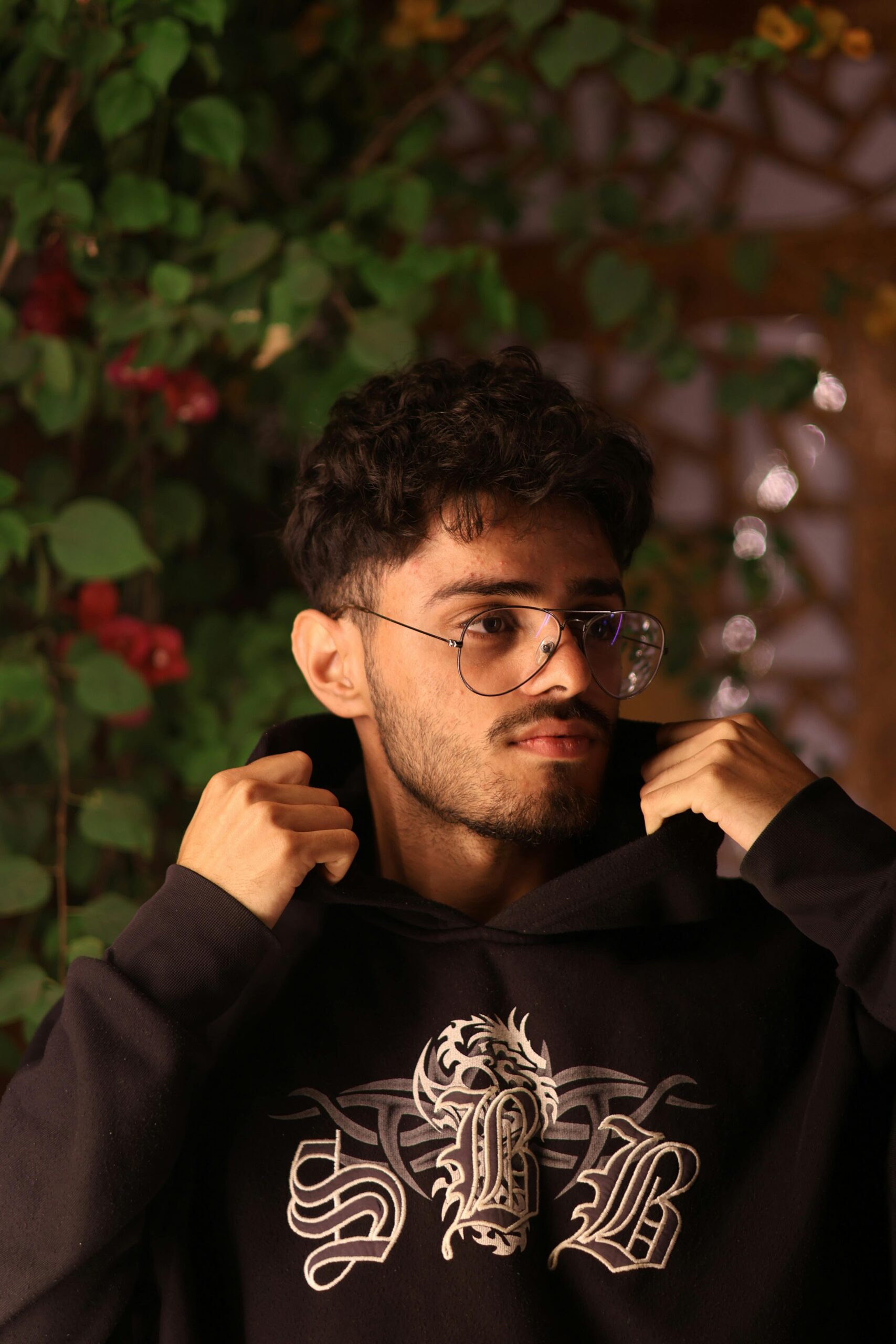 Portrait of a young man wearing a hoodie and glasses standing in Megrine, Tunisie.
